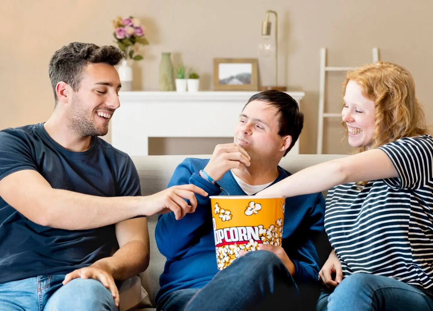 Front-facing view of three friends on a couch eating popcorn.